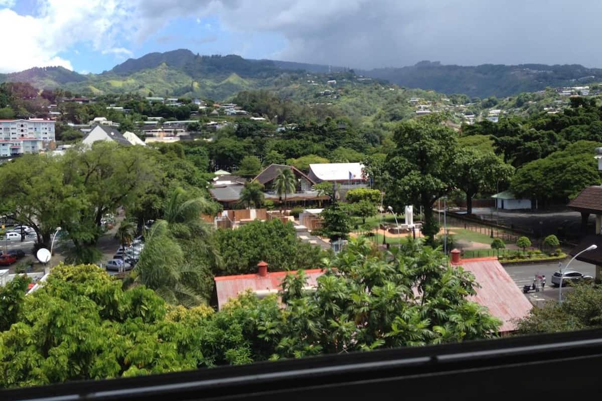 A residential area with houses, trees, and a hilly landscape in the background.