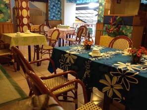 Um restaurante com várias mesas e cadeiras, algumas com toalhas de mesa floridas.