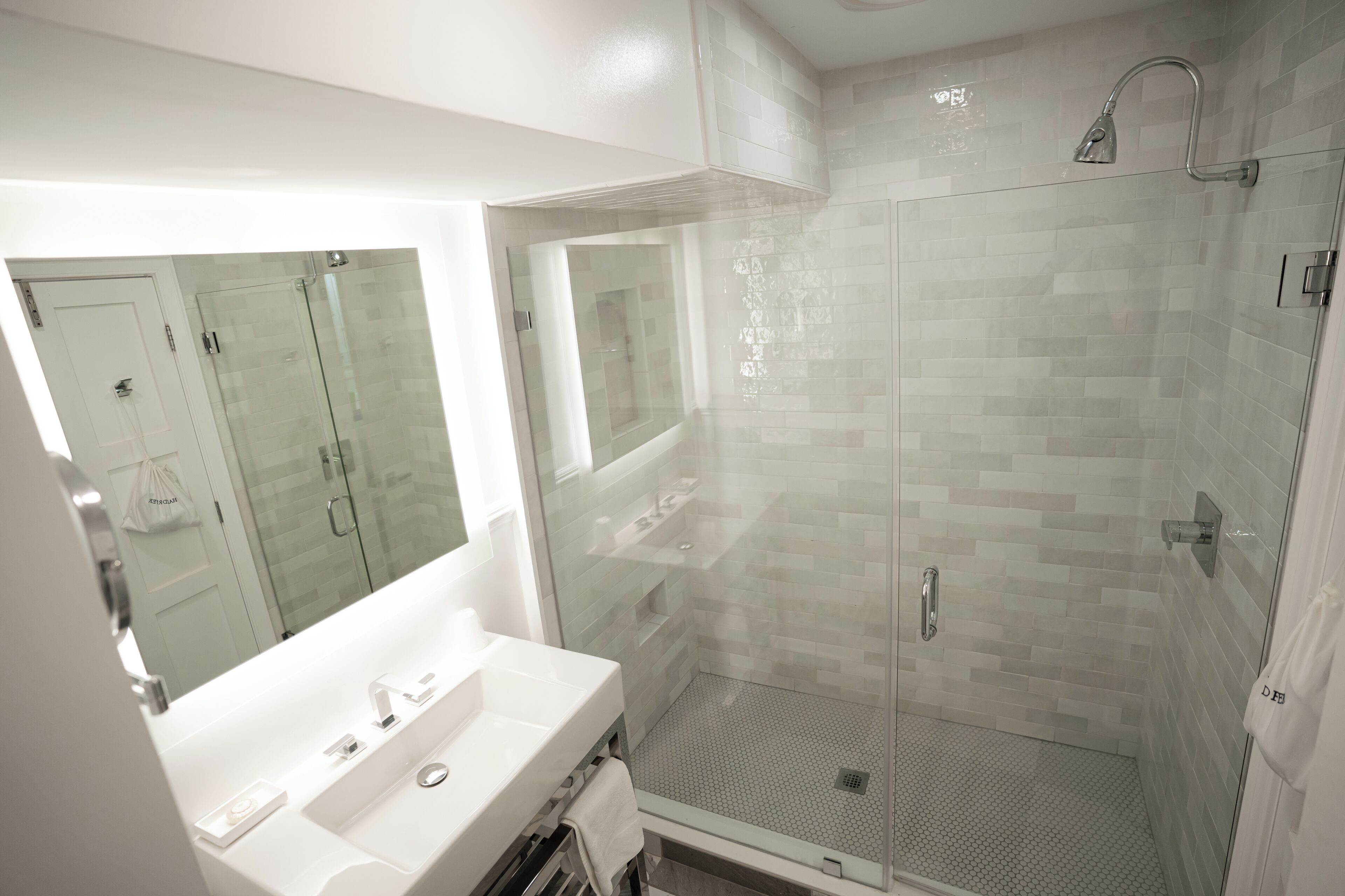 Un baño moderno con cabina de ducha de vidrio, un lavabo blanco y un espejo.