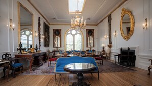 A grand room with a large blue sofa, ornate chandeliers, and classic furniture. - 20 South Battery (Charleston)