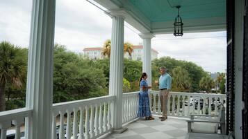 A covered porch with a checkered floor, white balustrades, and a hanging light fixture.