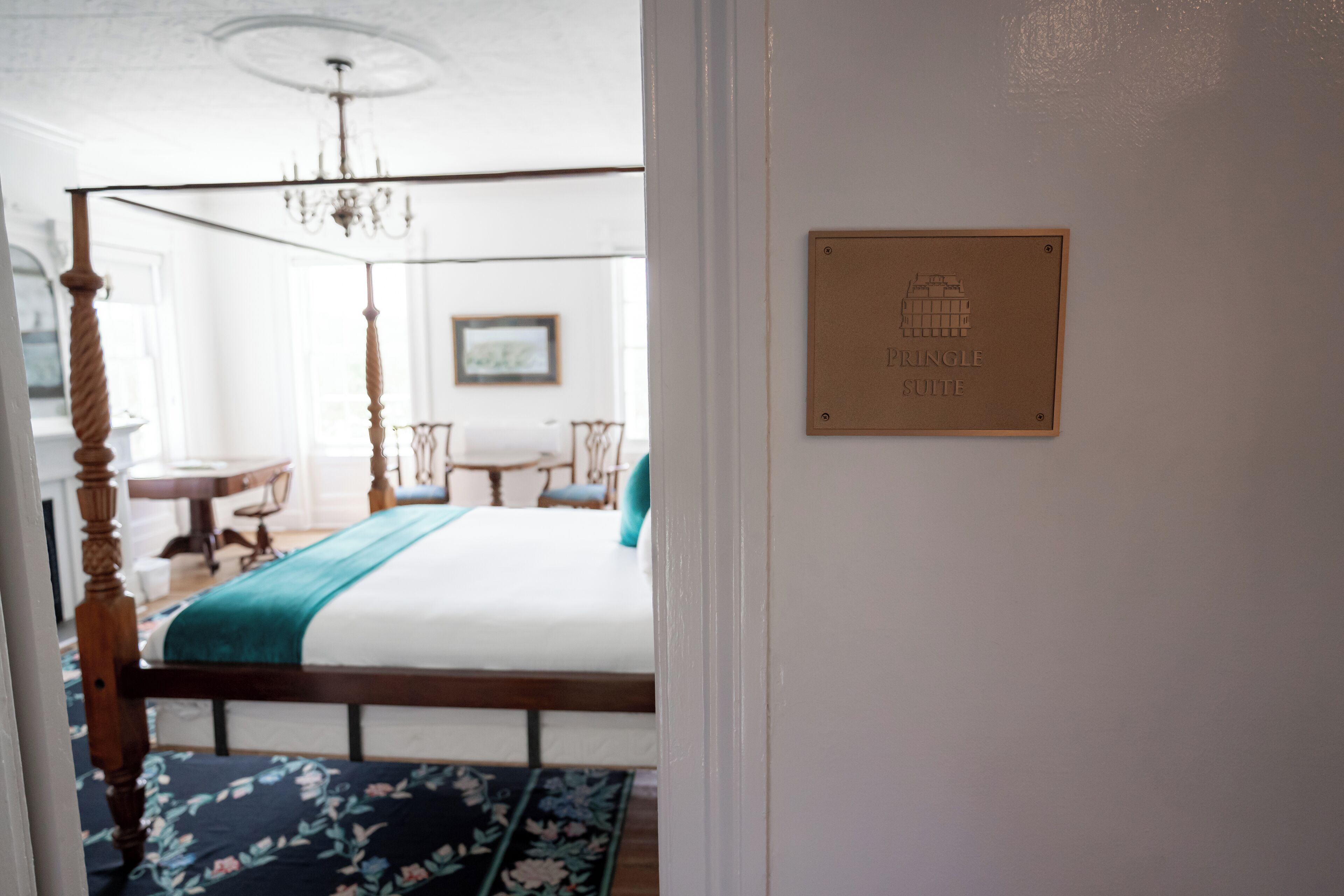 Un dormitorio con cama con dosel, una araña, una placa que dice "Pyramid Suite" y vistas de un comedor.