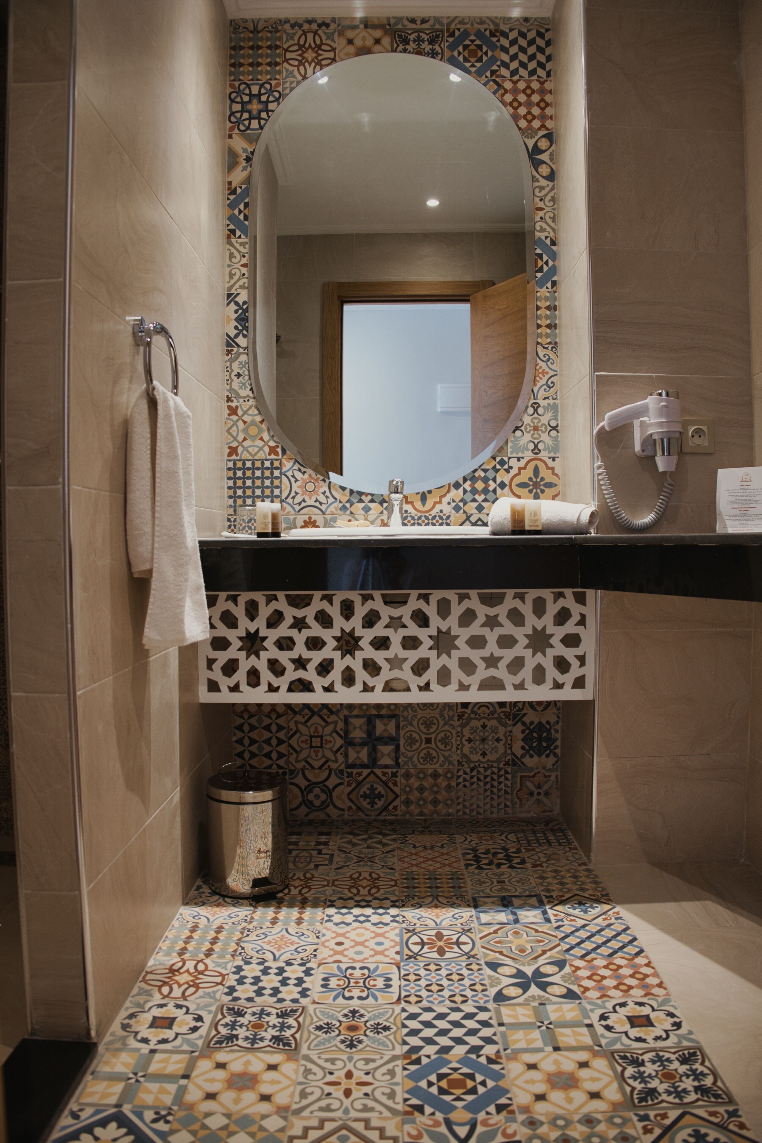 A bathroom with a tiled floor, a sink, a mirror, and a towel rack.