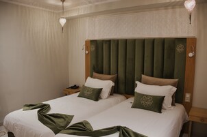 A hotel room with two beds, a wooden headboard, and a nightstand with a phone.
