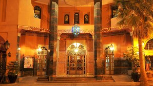 Het uiterlijk van Hotel Diwan met een opvallende ingang, meerdere vlaggen en een centrale boog.