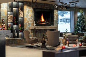 A modern living room with a stone fireplace, two sofas, and a Christmas tree. - Hotelli Kieppi (Saariselka)
