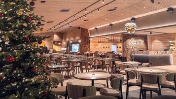 A spacious indoor area with multiple round tables and chairs, a Christmas tree, and a reception desk with the name 'KIEPI' on the wall.
