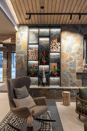 Un interior moderno con chimenea de piedra, zona de estar y plantas en macetas.