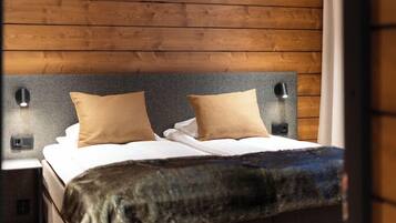 A bed with a headboard, two pillows, a blanket, and two bedside lamps.
