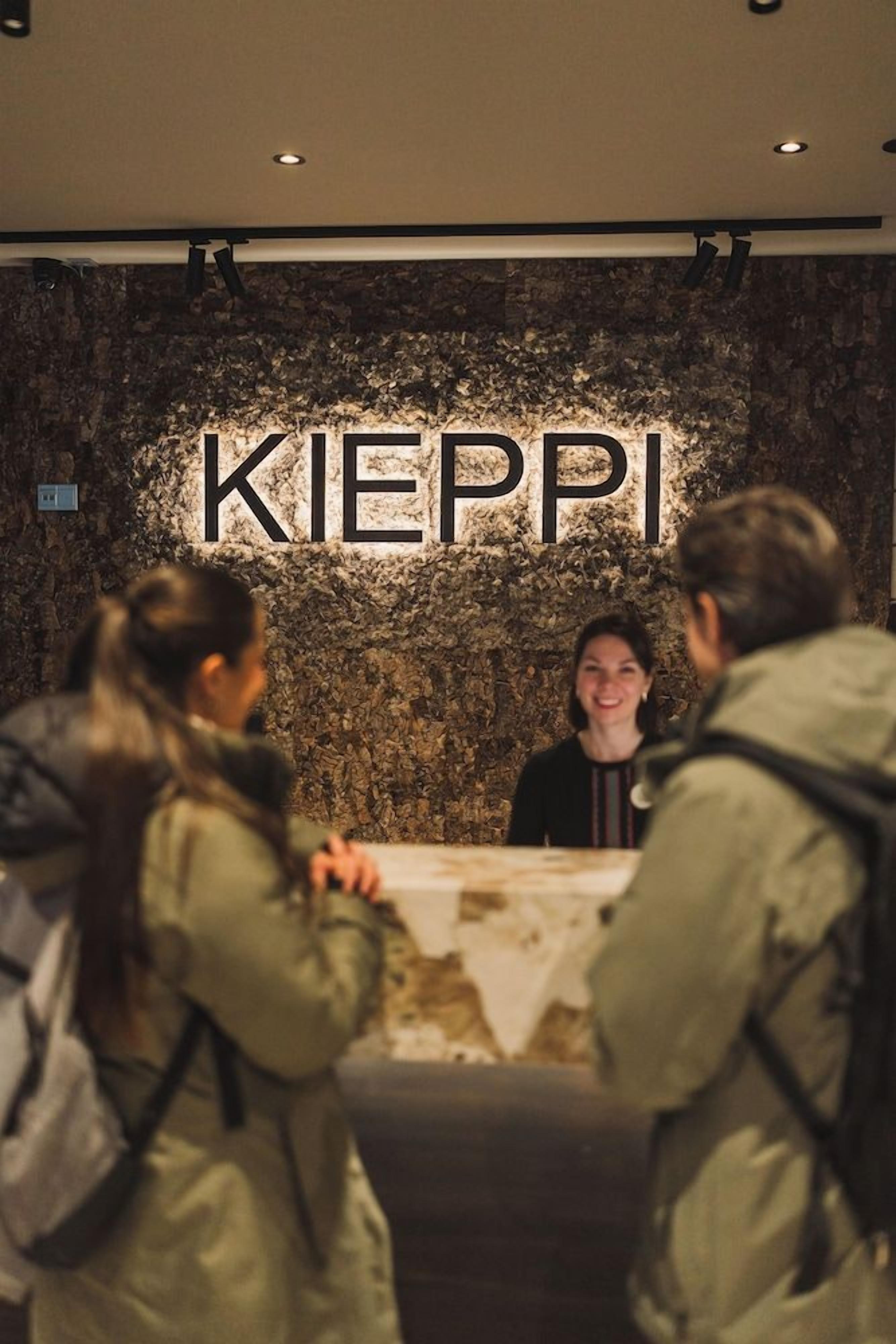 Zona de recepción con pared de piedra y un cartel que dice 'KIEPPI'.