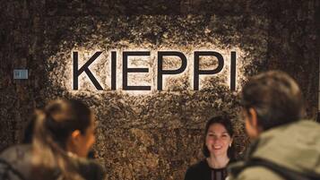 Zona de recepción con pared de piedra y un cartel que dice 'KIEPPI'.