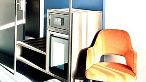 Una habitación con literas, un escritorio con computadora y una silla naranja.