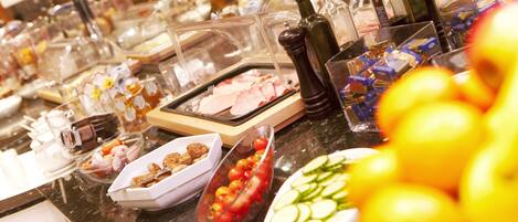 Un buffet proposant une variété de plats, notamment des viandes, des fromages et des fruits.