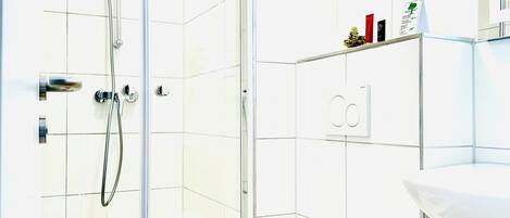 A modern bathroom with a glass-enclosed shower, a white toilet, and a sink with a mirror above it.
