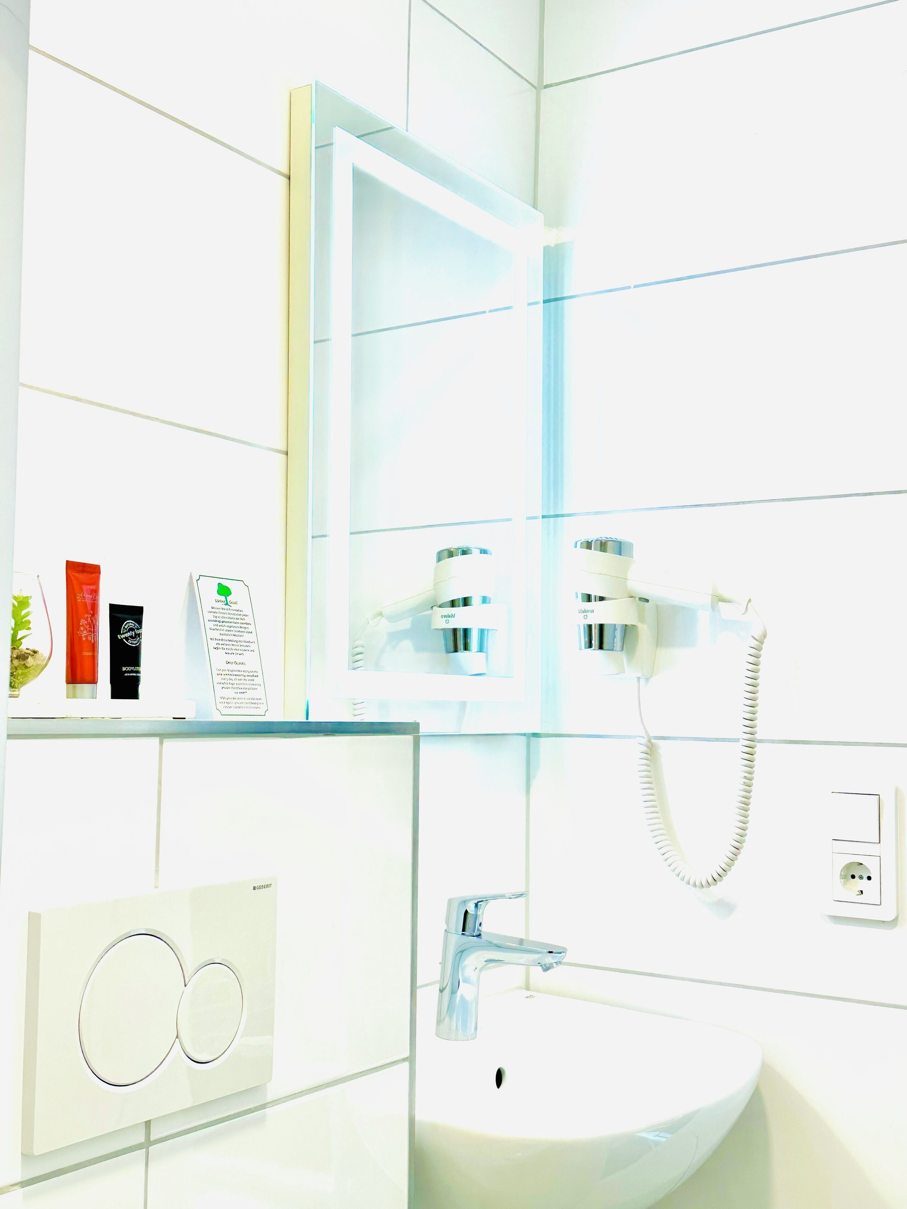 A bathroom with a white sink, a mirror, and a telephone. There are toiletries on the counter.