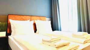 Habitación de hotel con cama, almohadas, mesita de noche y ventana con cortinas.