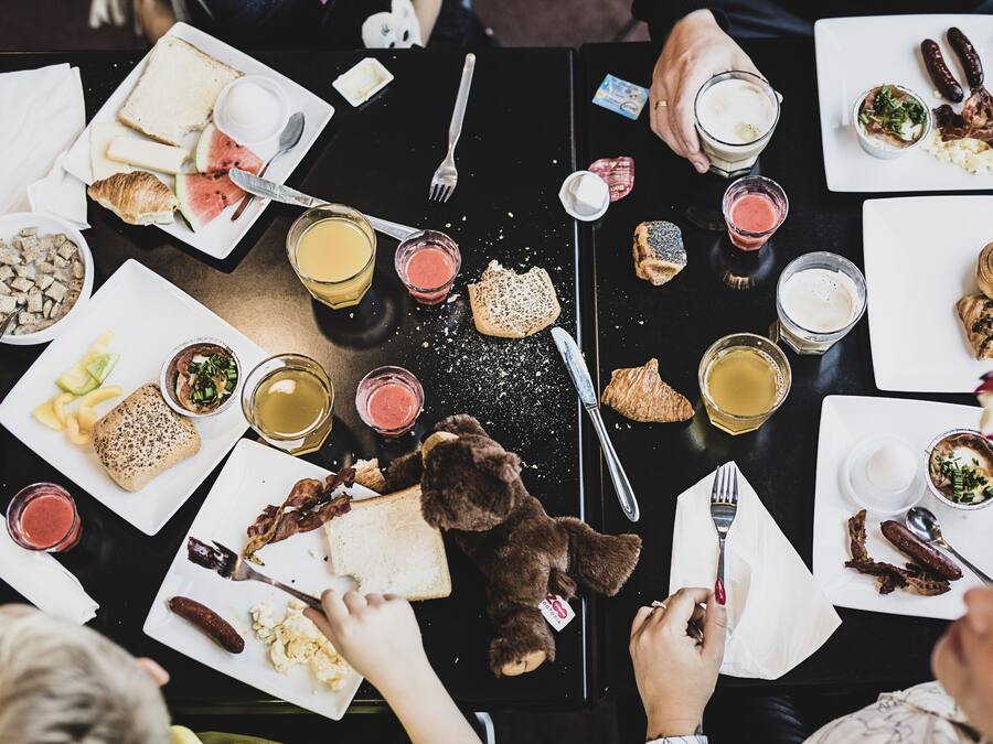 Een eettafel met diverse gerechten en bestek, wat een maaltijdsetting aangeeft.