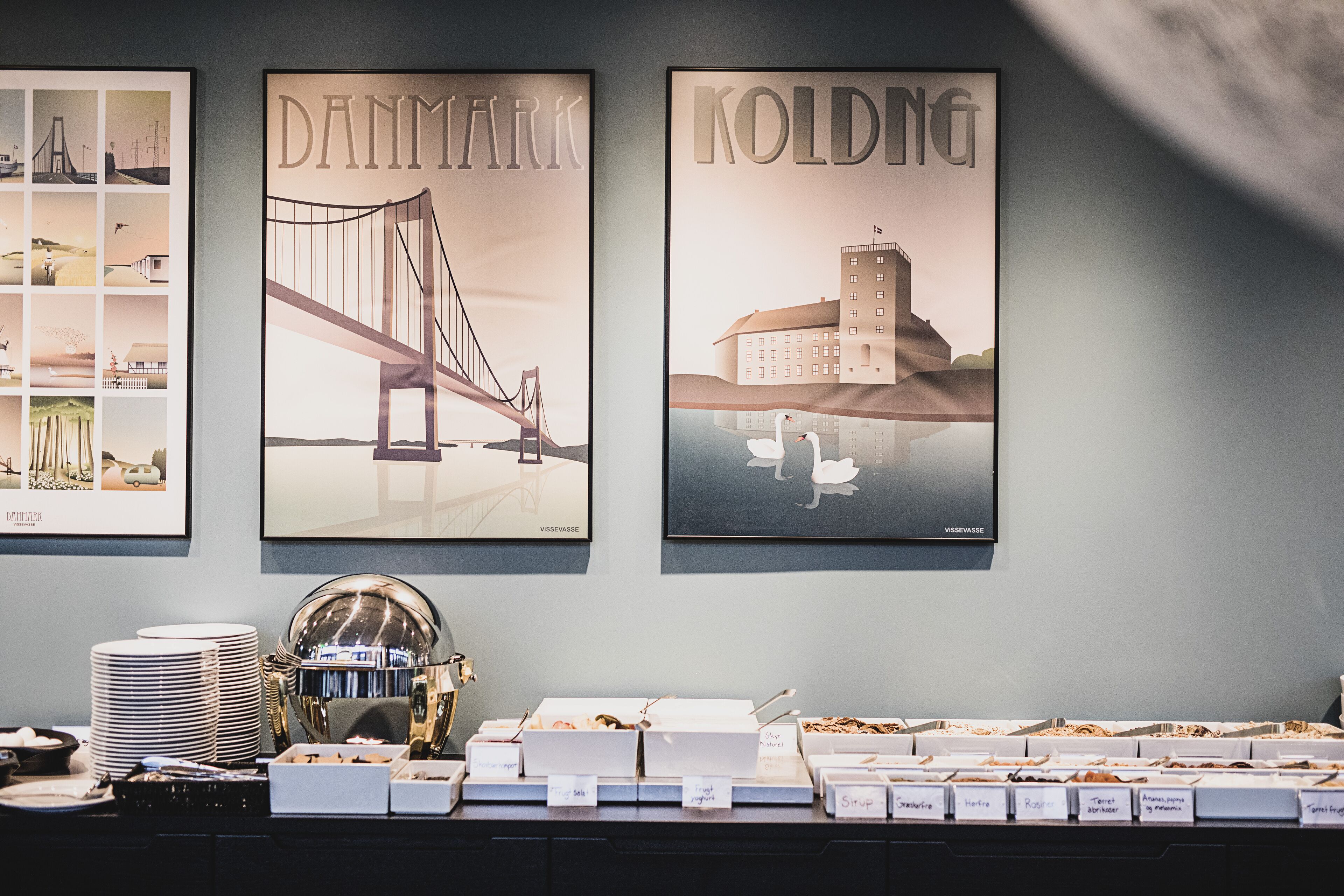 Three framed posters of bridges and a buffet area with labeled food containers.