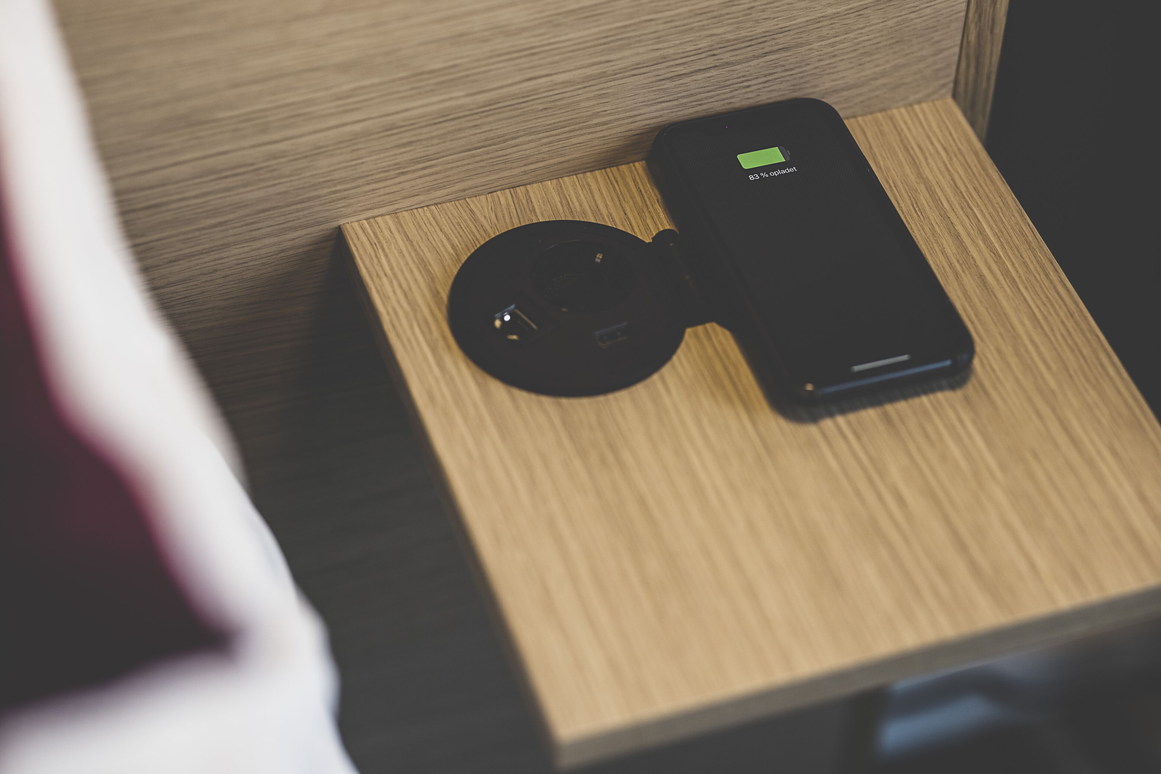 A black portable device with a green battery indicator on a wooden surface.