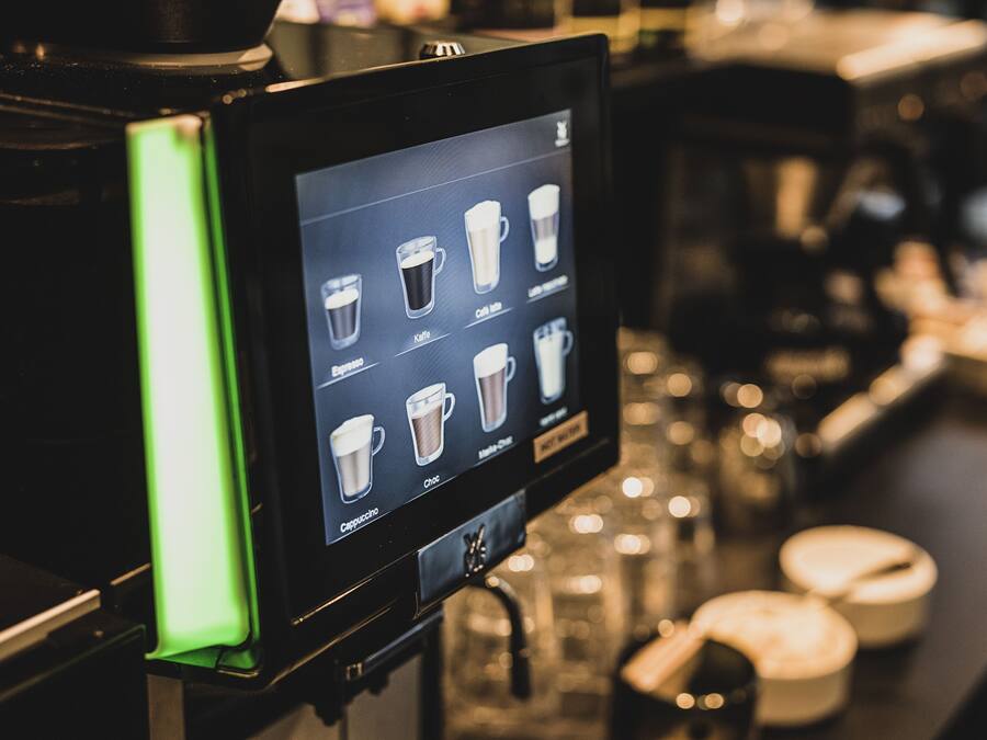 Ein digitales Menü an einer Kaffeemaschine mit verschiedenen Getränkeoptionen.