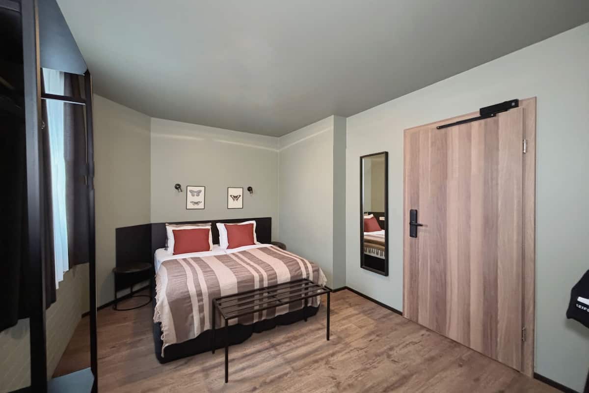 Une chambre à coucher comprenant un lit, une armoire en bois, un miroir et deux cadres photo accrochés au mur.