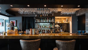 Eine Bar mit einer Theke, Flaschenregalen und zwei Ledersesseln.