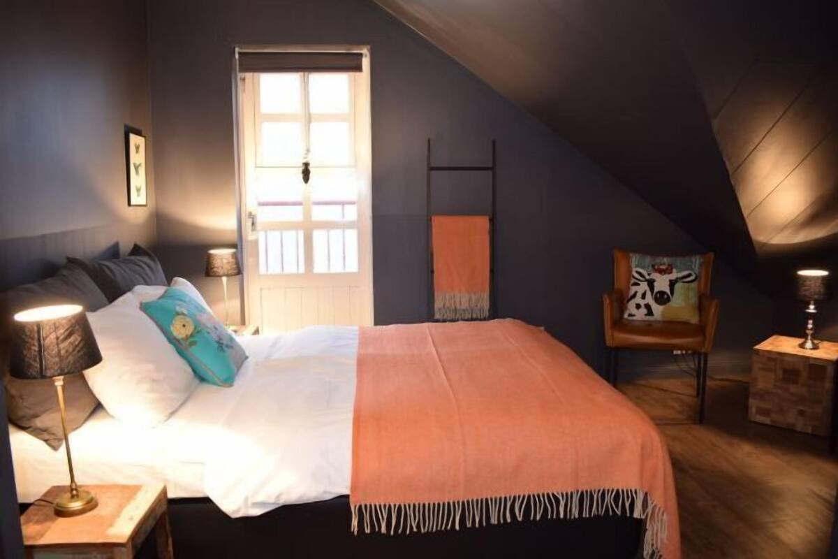 Ein Schlafzimmer mit Bett, Stuhl, Lampe, Tür und Fenster.