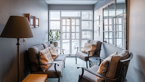 Ein gemütlicher Sitzbereich mit einer Couch und Sesseln, einer Stehlampe und einem großen Fenster mit Blick.