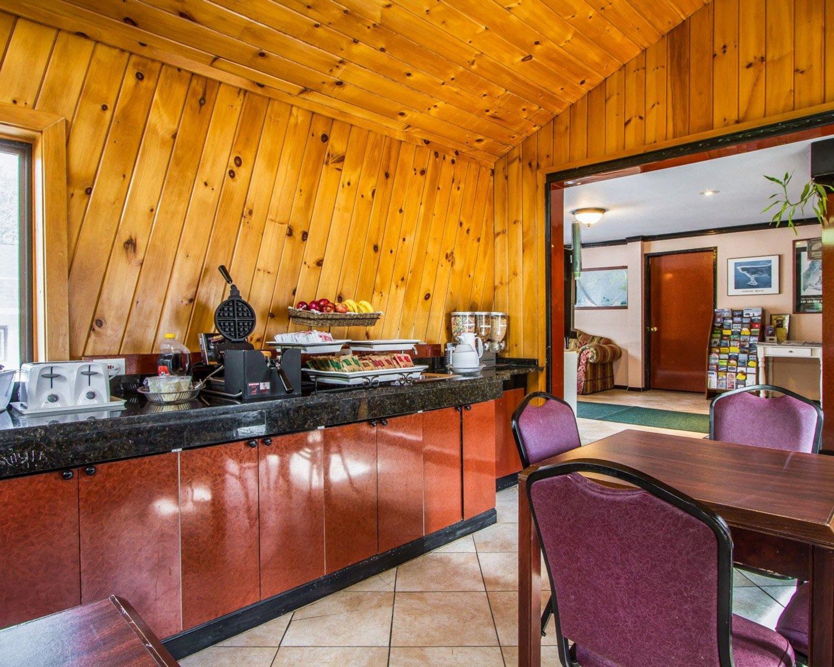 A wooden-paneled kitchen with a breakfast bar, a waffle maker, and a fruit basket.