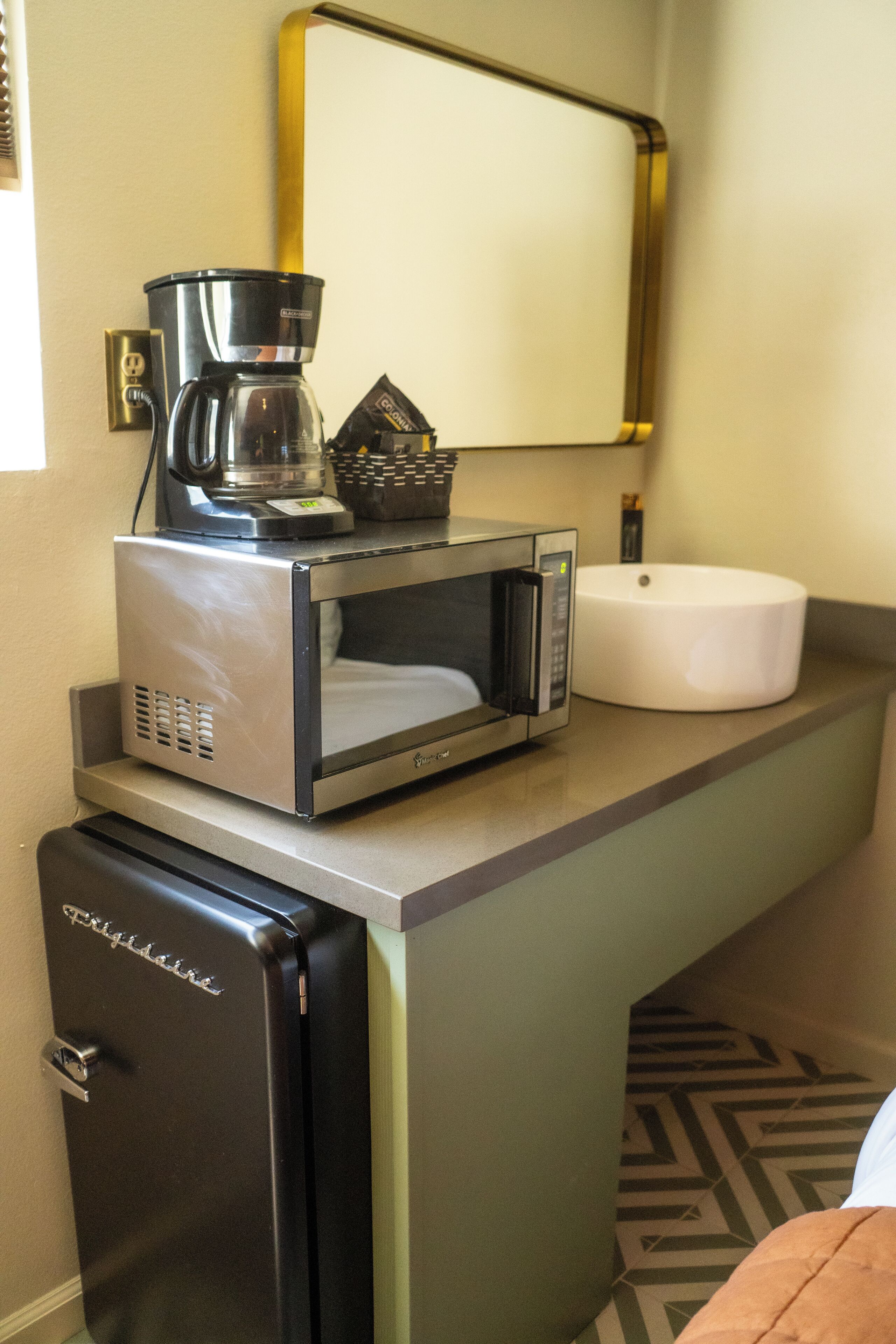 Een kleine keuken met een koffiezetapparaat, magnetron en koelkast.