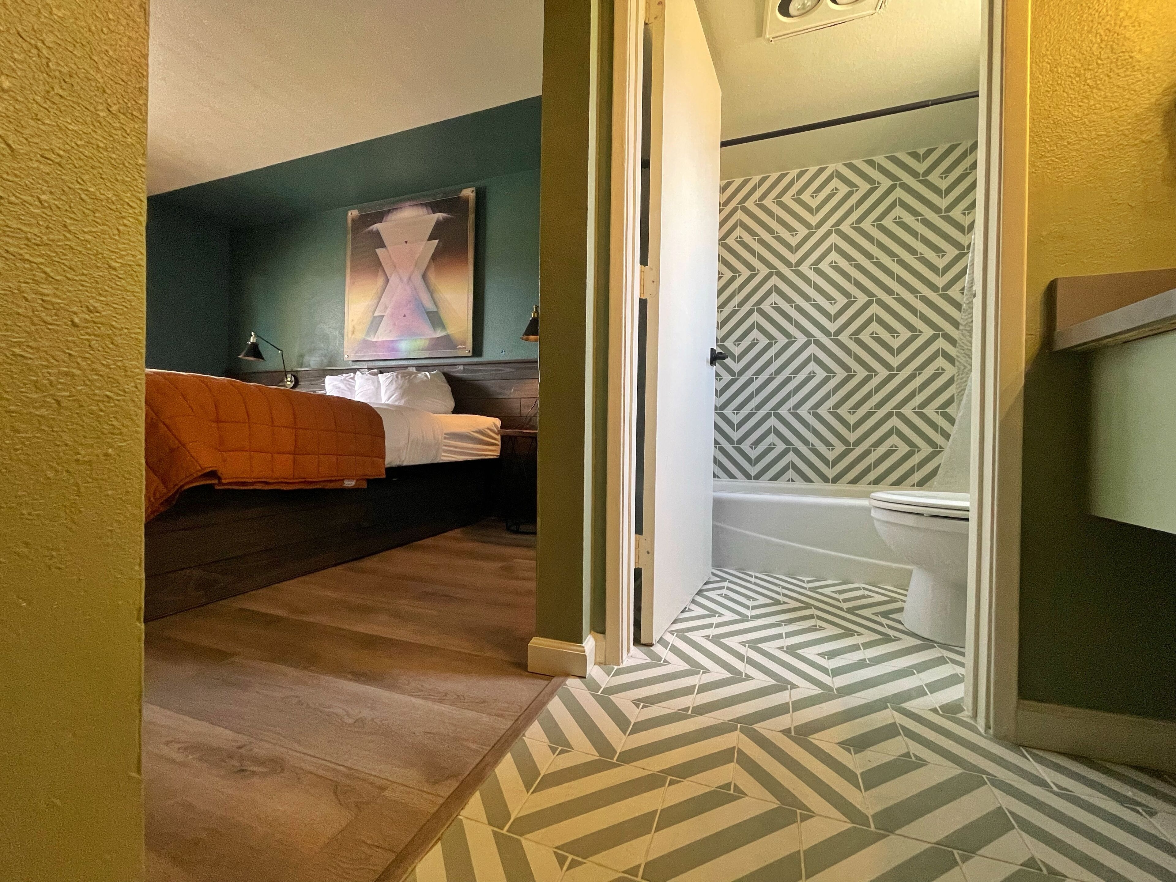 A bedroom with a bed, a nightstand, and a painting on the wall.