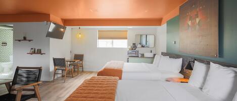 A hotel room with a large bed, a desk, a chair, a TV, and a window with blinds.