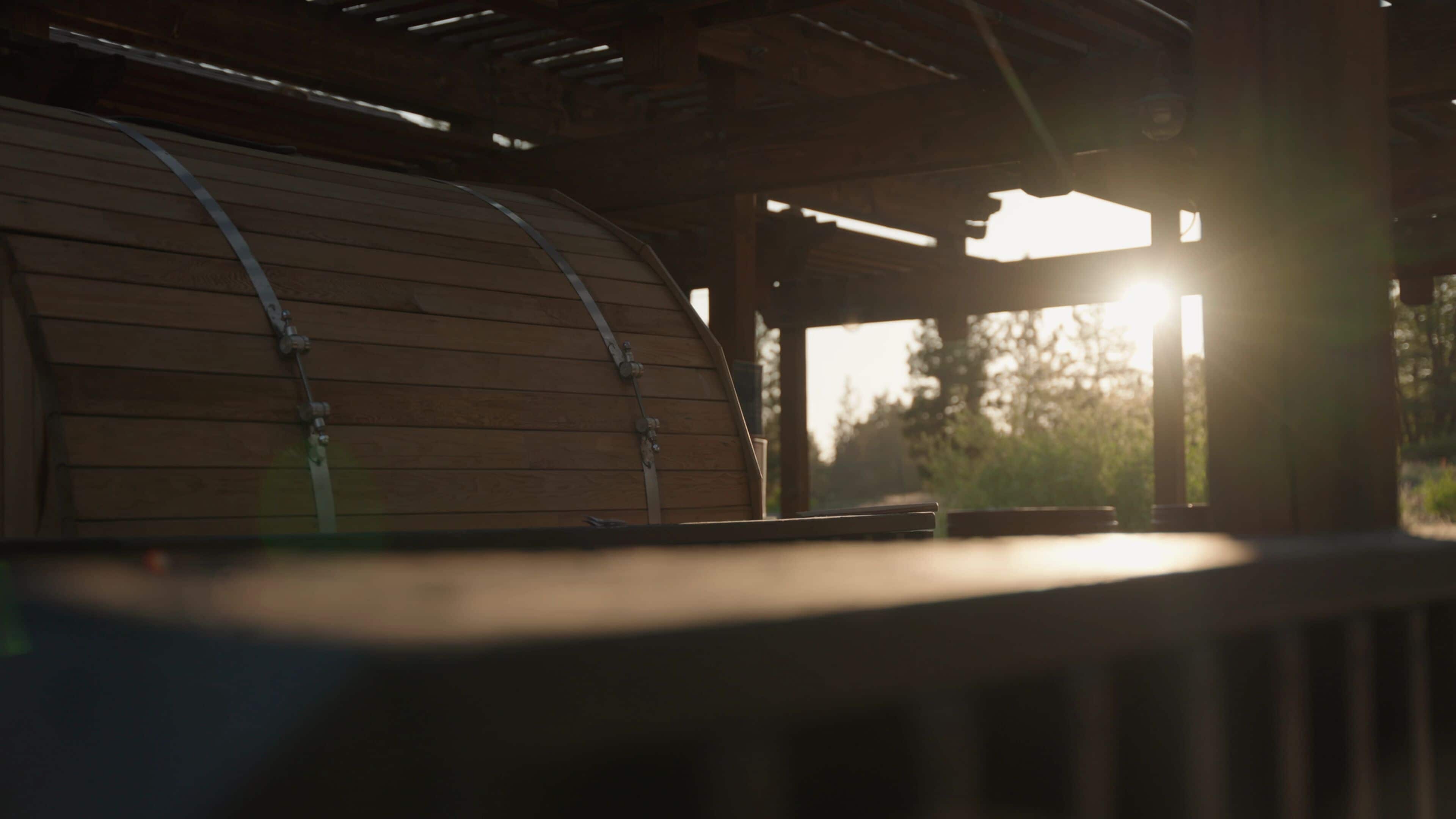 A wooden barrel structure with metal straps, likely part of a rustic building or outdoor seating area.