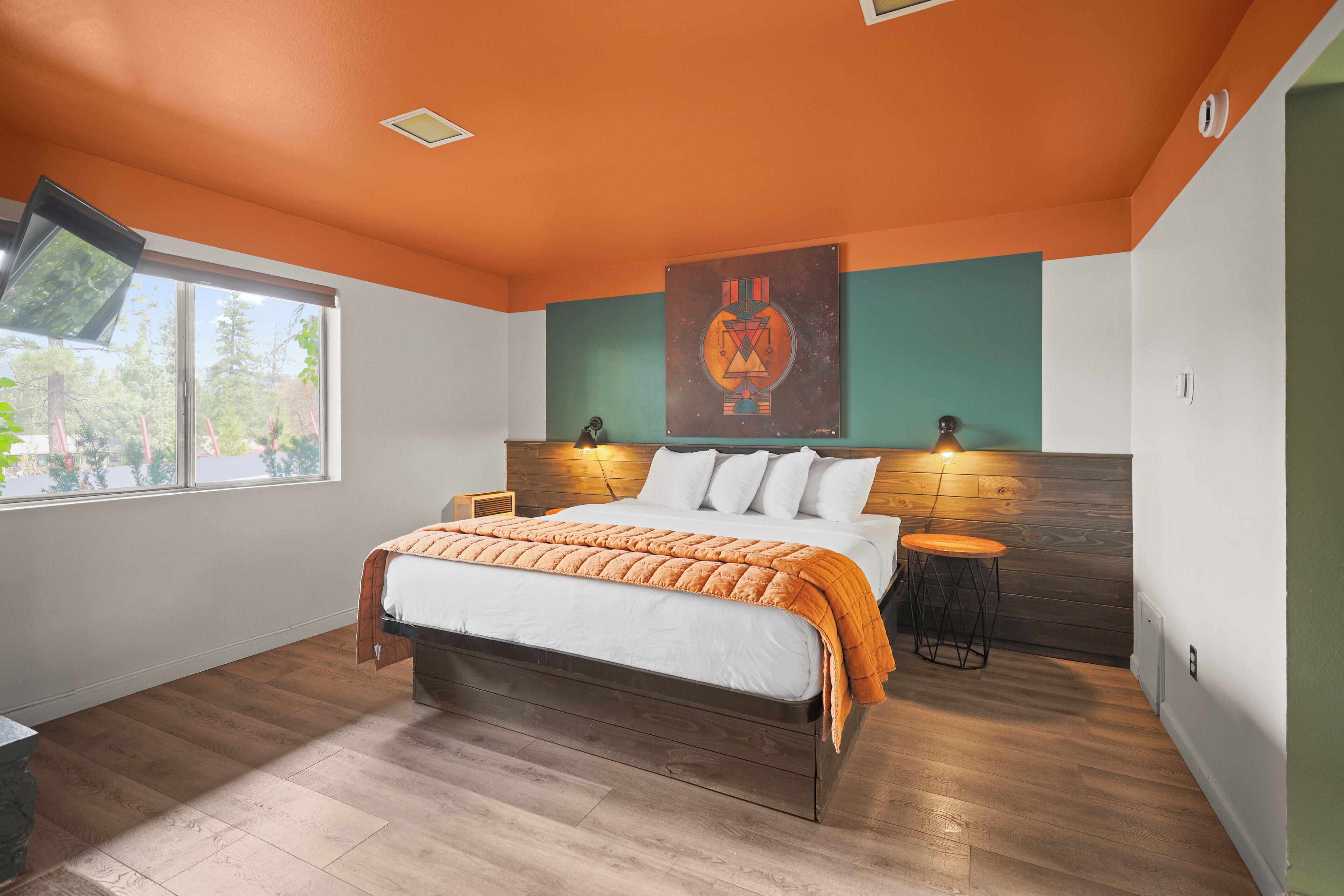 Una camera da letto moderna con un letto grande, due lampade ai comodini, una finestra e un'opera d'arte appesa al muro.