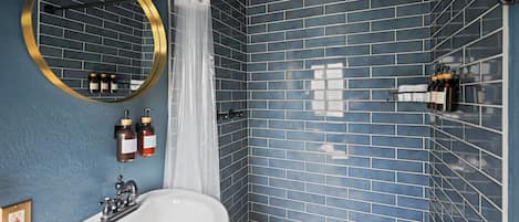 A bathroom with a white sink, a round mirror, and blue-tiled walls.