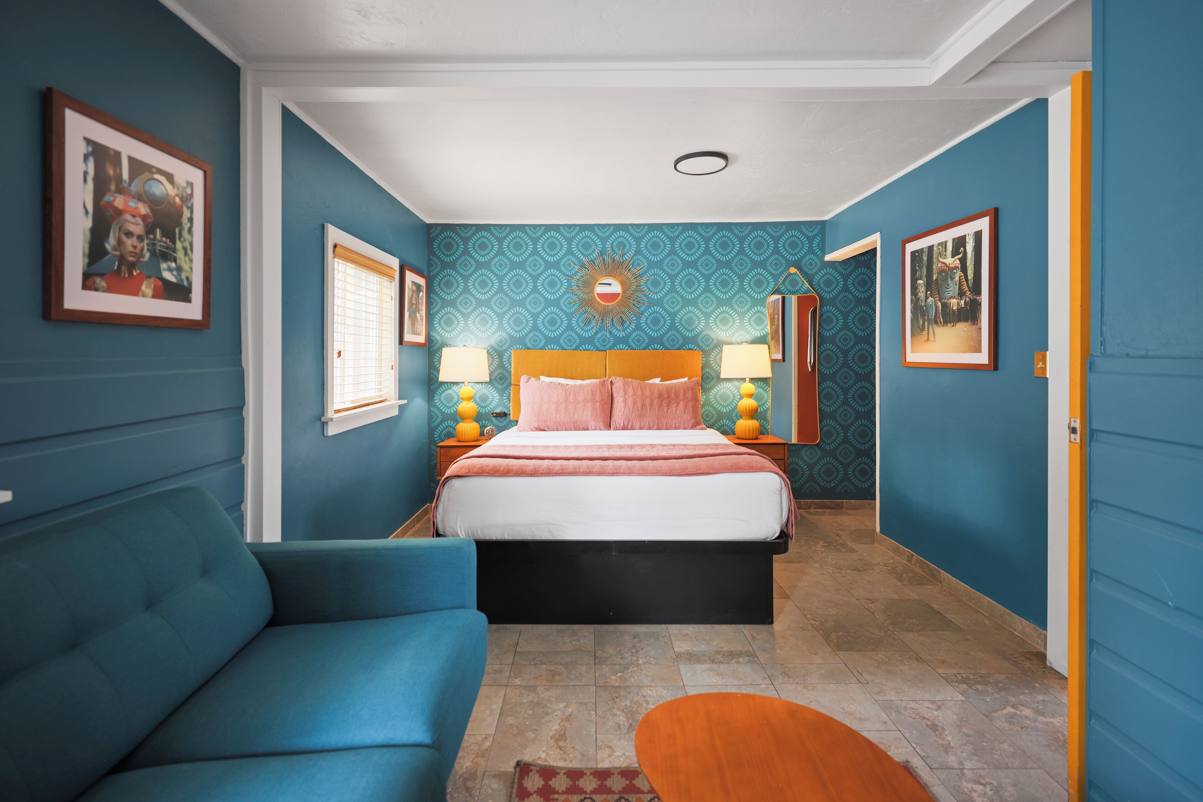 Une chambre à coucher avec un lit, un canapé bleu et une table de chevet avec des lampes.