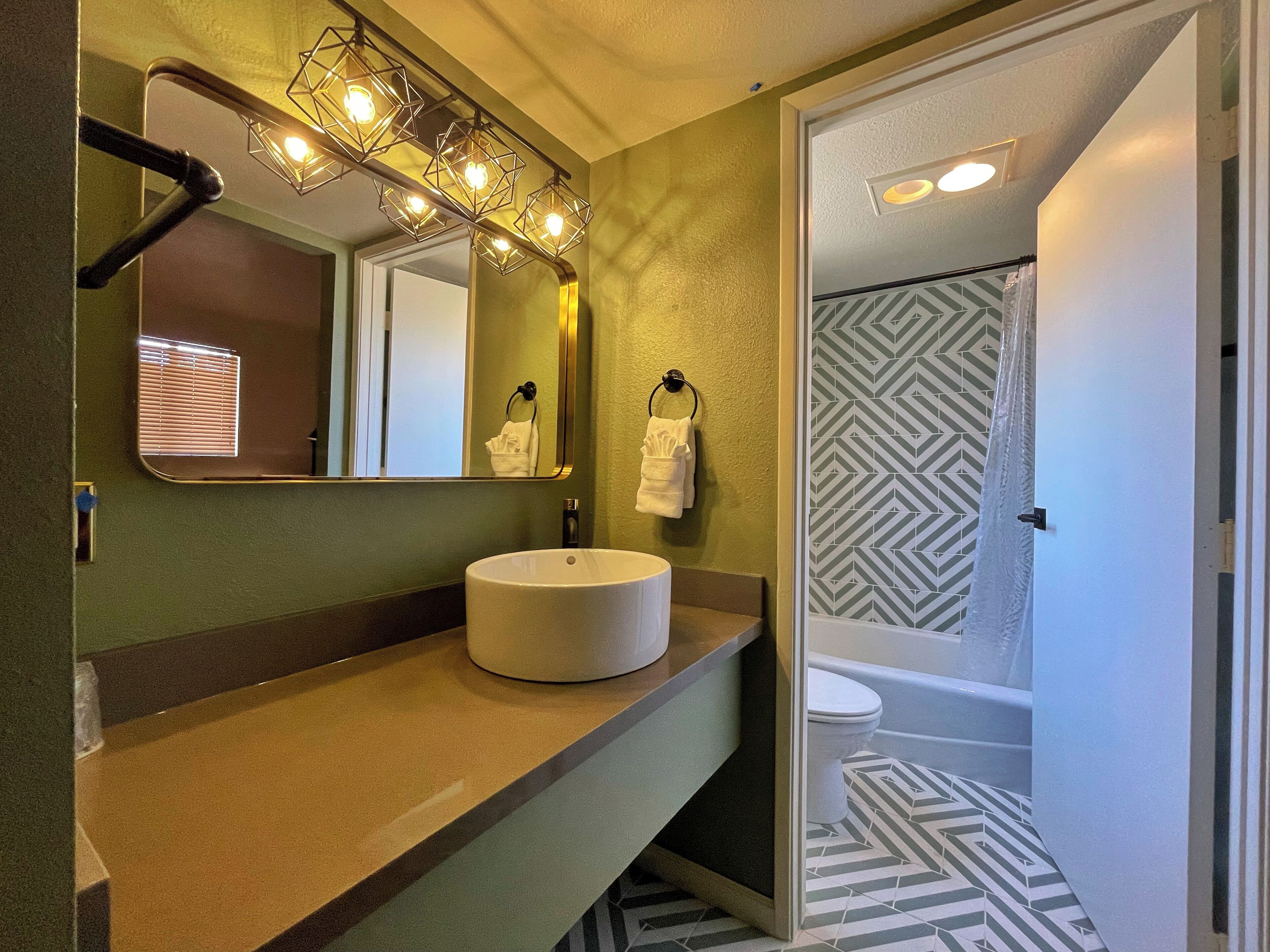 A bathroom with a vanity, a sink, a mirror, and a shower area.