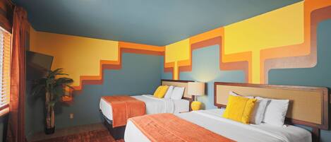 A hotel room with two beds, a large potted plant, and a patterned rug.