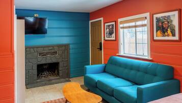 A living room with a stone fireplace, a blue sofa, and a television mounted on the wall.