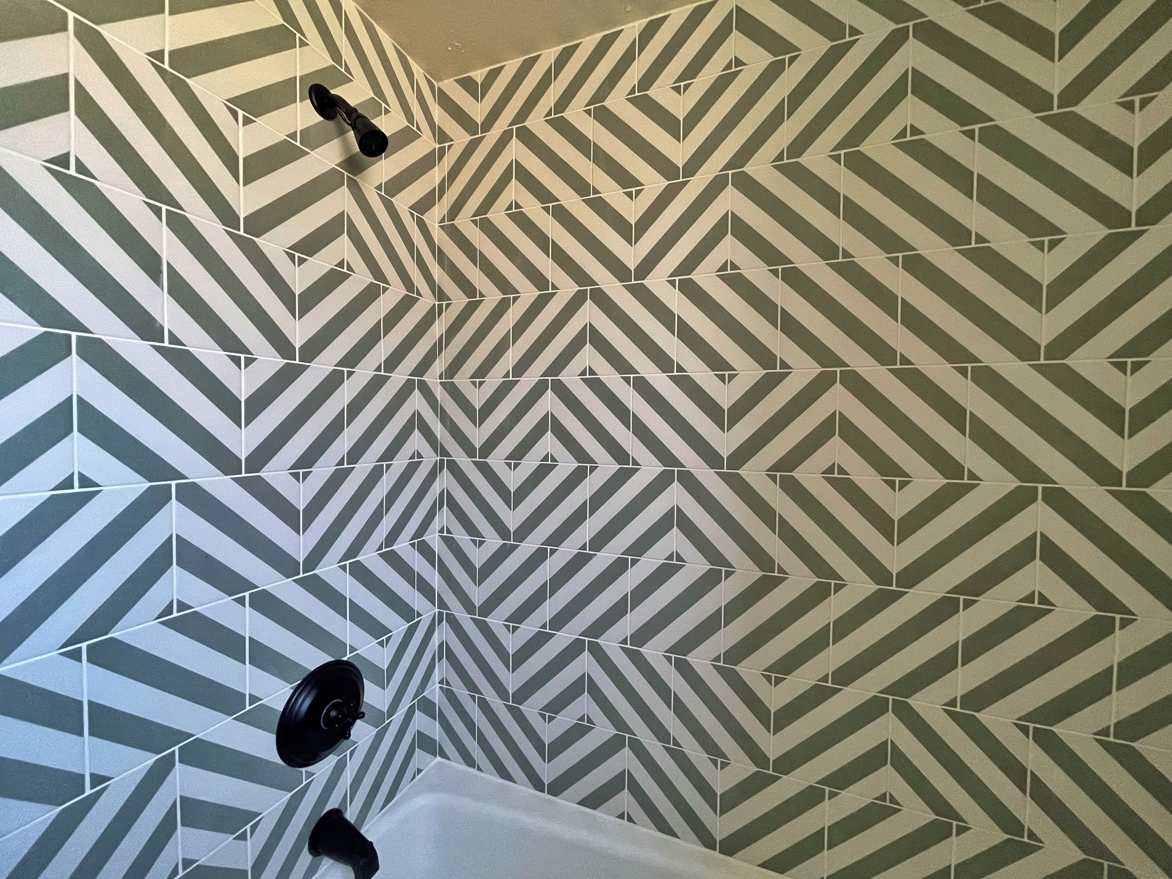 Un baño con piso de baldosas estampadas con motivos geométricos y una bañera blanca.