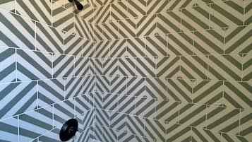 A bathroom with a geometric patterned tile floor and a white bathtub.