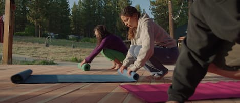 A wooden deck with yoga mats and a person in a purple top.
