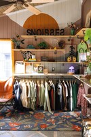 A room with a clothing rack, shelves with various items, and a sign with letters.