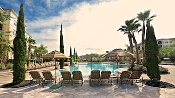 Una piscina al aire libre, sombrillas, sillones reclinables de piscina