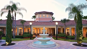 A hotel with a central fountain, palm trees, and a tiled roof. - WorldQuest Orlando Resort (Orlando)