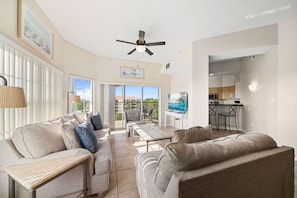 A spacious living area with a sofa, a coffee table, and a television. There is a balcony with a view of the outdoors. - WorldQuest Orlando Resort (Orlando)