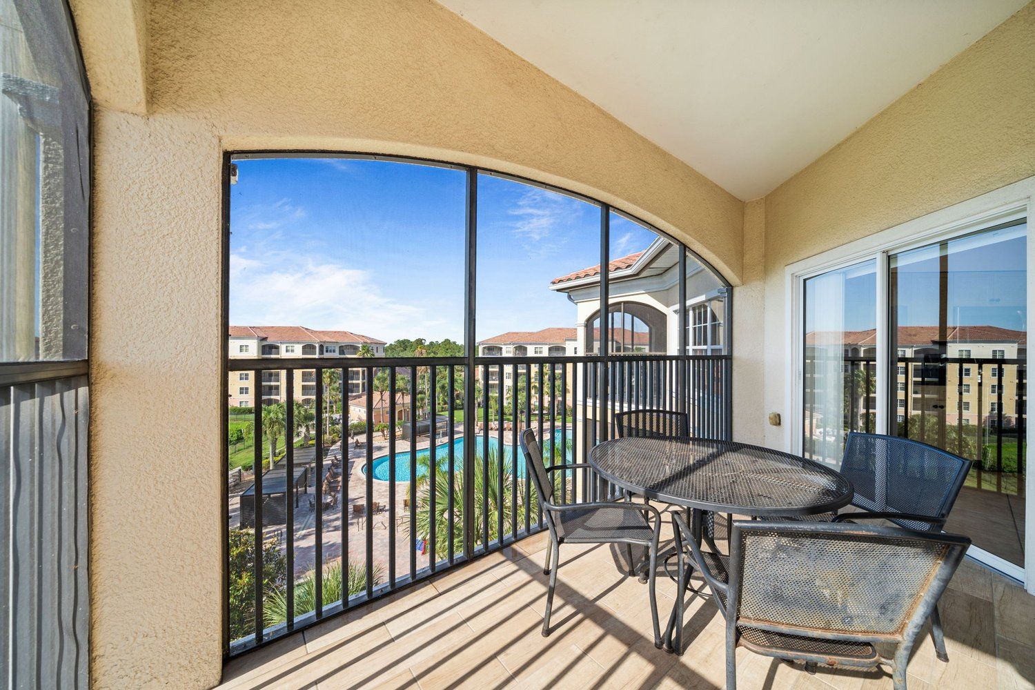 A balcony with a view of a swimming pool and surrounding buildings.