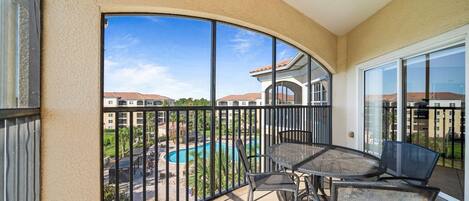 A balcony with a view of a swimming pool and surrounding buildings.