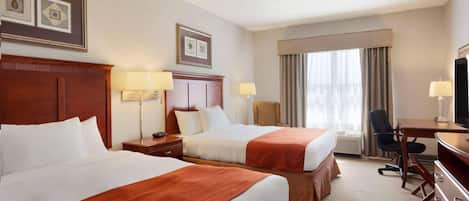 A hotel room with two beds, a desk, a chair, and a television.