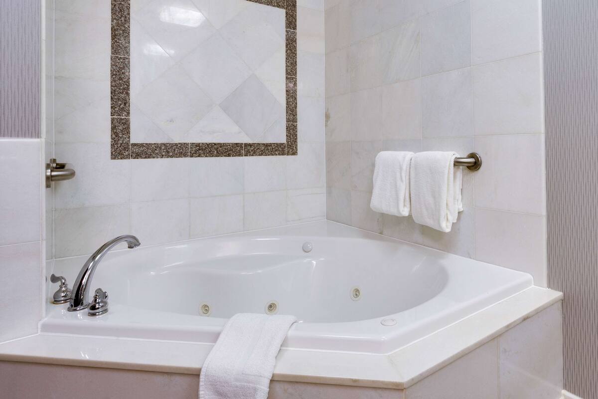 Une salle de bain avec une baignoire sur pieds, un porte-serviettes et un miroir doté d’un cadre décoratif.